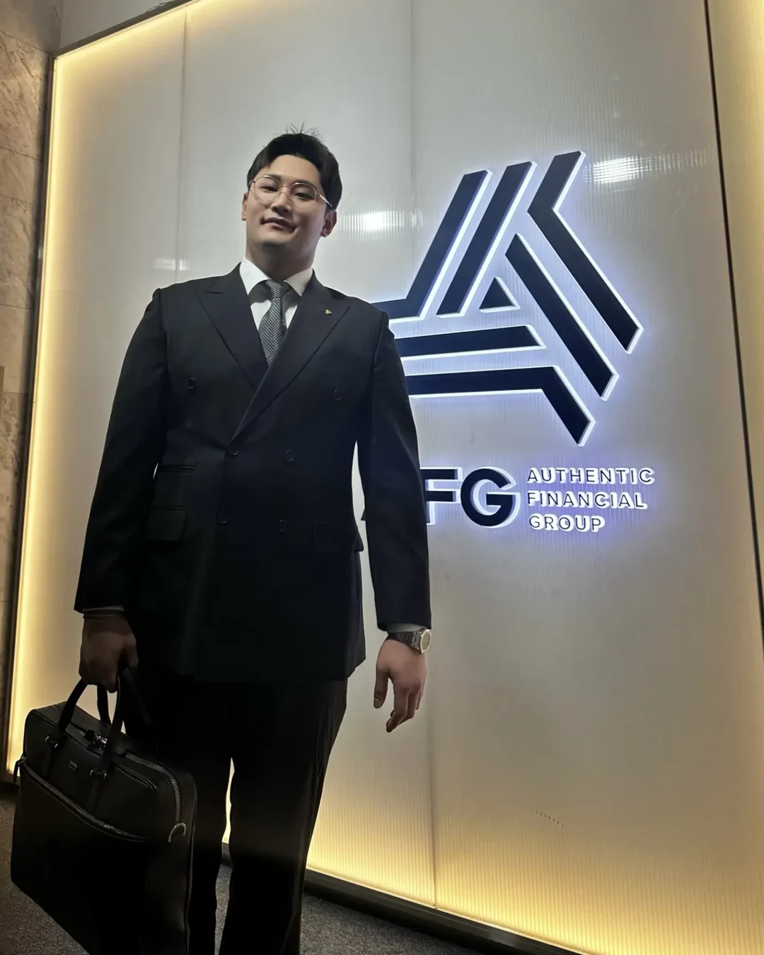 회사 로고 앞에 정장 차림으로 선 김수빈 전무이사